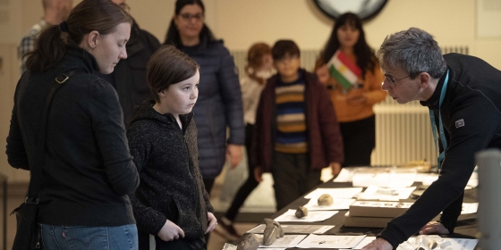 En famile i tett dialog med forsker ved Universitetsmuseet mens de studerer arkeologiske funn.