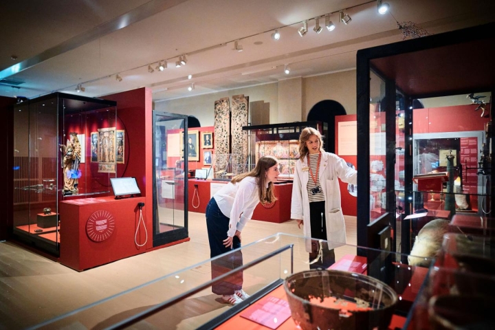 oversiktsbilde av jubileumsutstillingen, to verter ser på gjennstandene